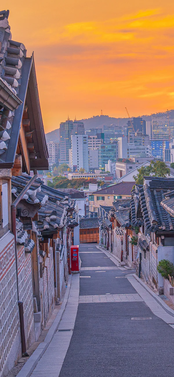 Zonsondergang boven Bukchon Hanok Village in Seoul, Zuid-Korea, met de skyline van de stad op de achtergrond