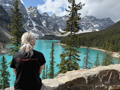 Een vrouw in een TourCompass T-shirt staart uit over het water van Lake Louise in Canada