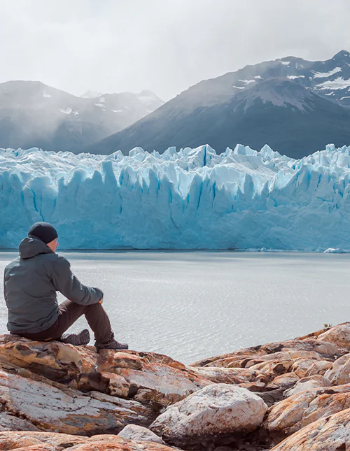 Man zittend voor de Perito Moreno-gletsjer in nationaal park Los Glaciares