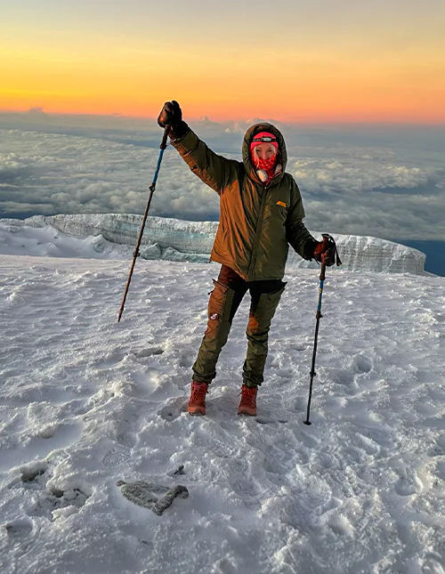 Cat van TourCompass staat bij zonsopkomst op de top van de Kilimanjaro