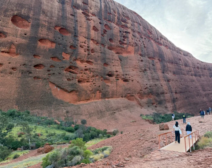 Walpa Gorge bij Kata Tjuta in Australië, met wandelaars op een pad langs de enorme rode rotswand