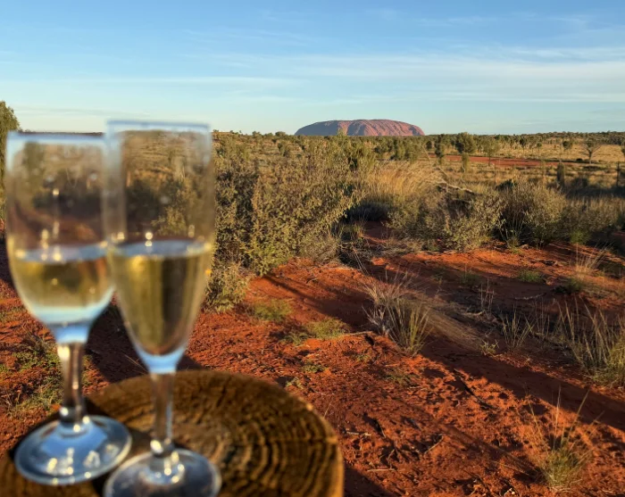 Twee glazen mousserende wijn met uitzicht op Uluru in Australië en het rode woestijnlandschap