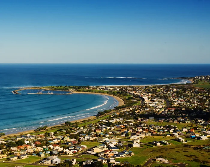 Apollo Bay in Australië, met een halvemaanvormig zandstrand, een blauwe zee en het stadje langs de kust