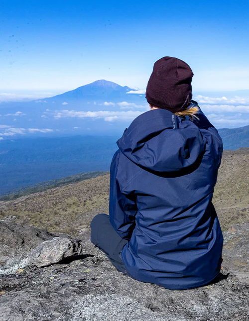 Vrouw die op een bergtop zit en geniet van het uitzicht