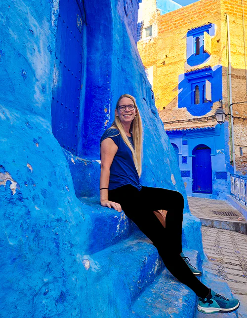 Een vrouw zit op de traptreden in de blauwe stad Chefchaouen in Marokko