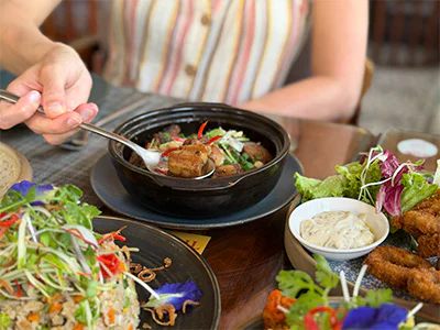 Hand van een vrouw die met een lepel naar eten reikt in Vietnam