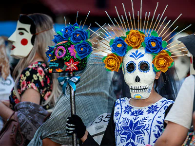 Vrouw uitgedost met een skeletgezicht en bloemen in haar haar voor de Mexicaanse Dag van de Doden