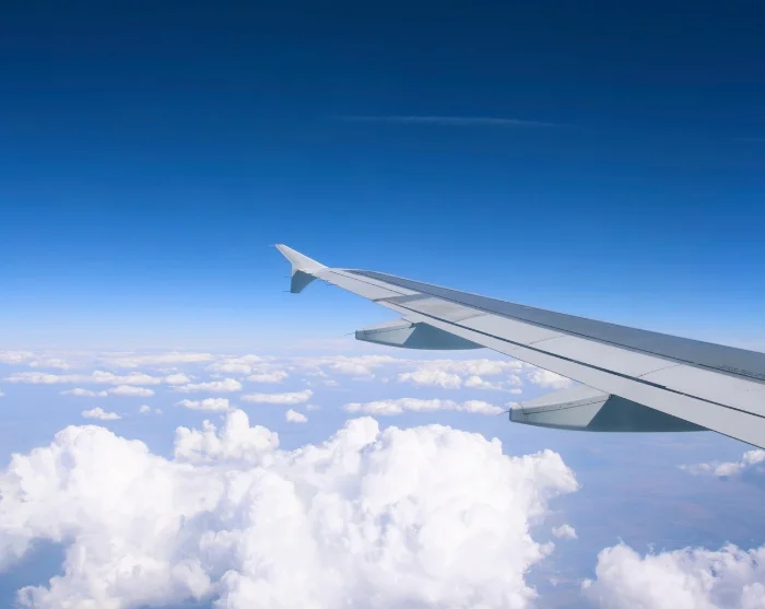 Vliegtuigvleugel boven de wolken, onderweg naar de bestemming