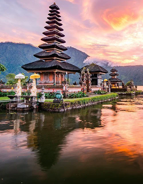 Prachtige tempel aan een meer bij zonsondergang, waar de bergen in het water weerspiegelen.