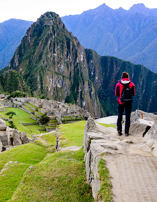 Een persoon die staat en uitkijkt over Machu Picchu