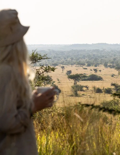 Vrouw die uitkijkt over het savannelandschap