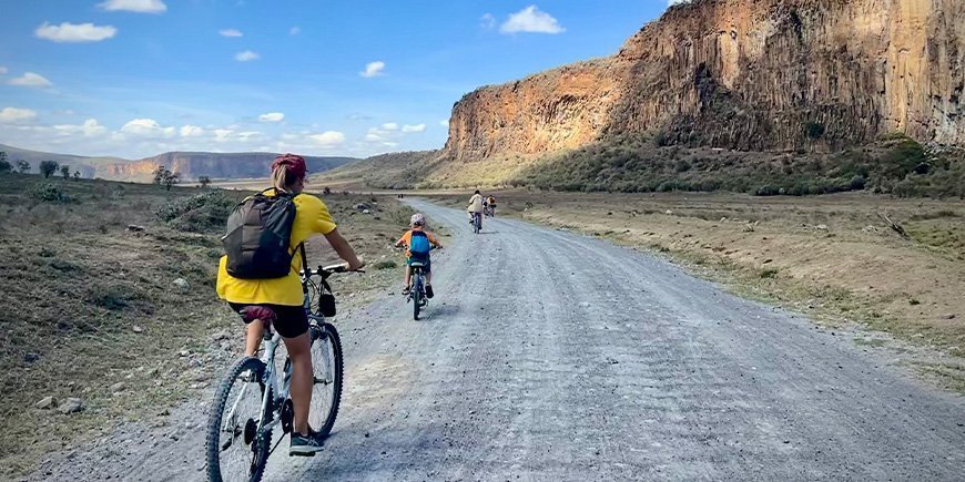 Vrouw en gezin fietsen in Hells Gate National Park in Kenia.