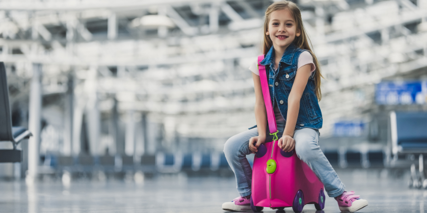 Kind zit op een koffer in een luchthaven