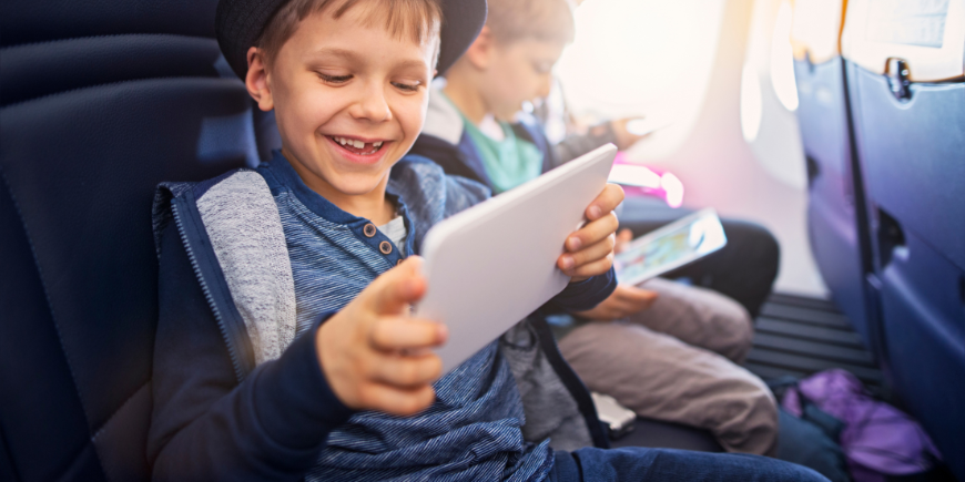 Kinderen spelen met een iPad in het vliegtuig
