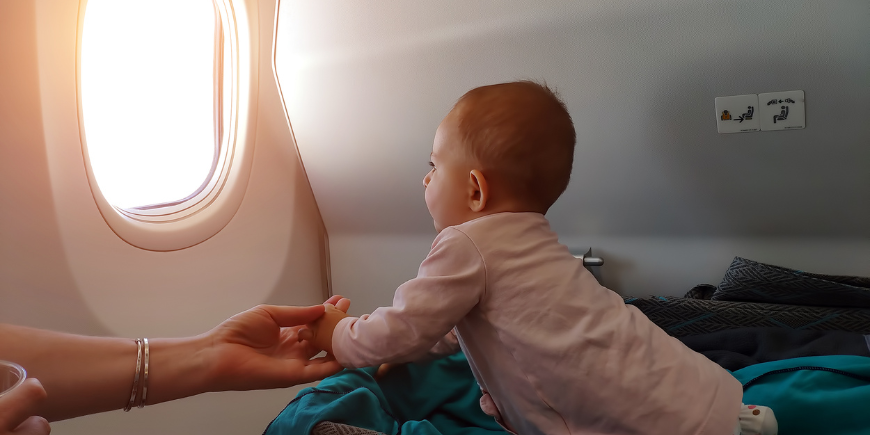 Baby kijkt uit het vliegtuigraampje