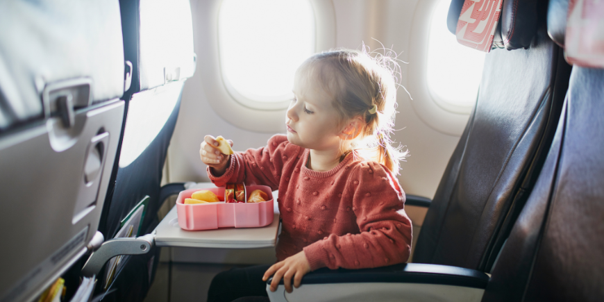 Kind eet hapje in de vliegtuigstoel