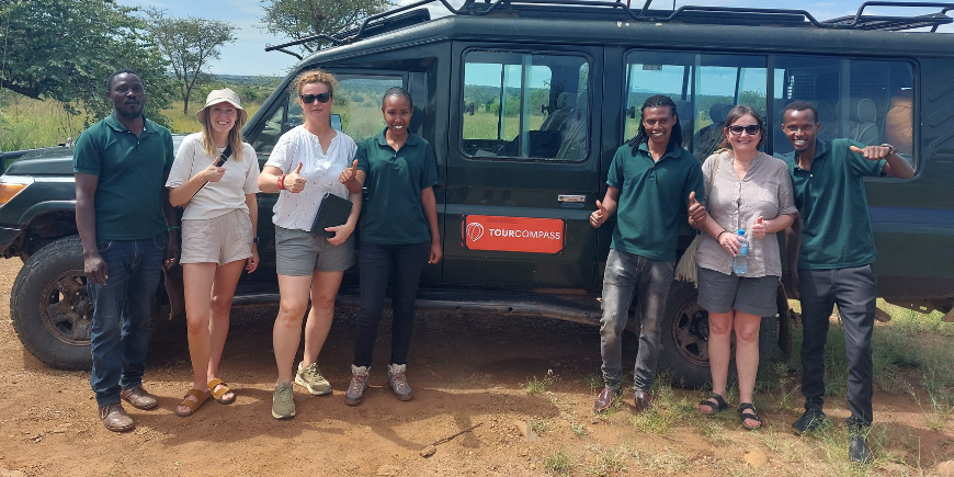 Safarigangers en gidsen staan bij een safariwagen in Afrika.