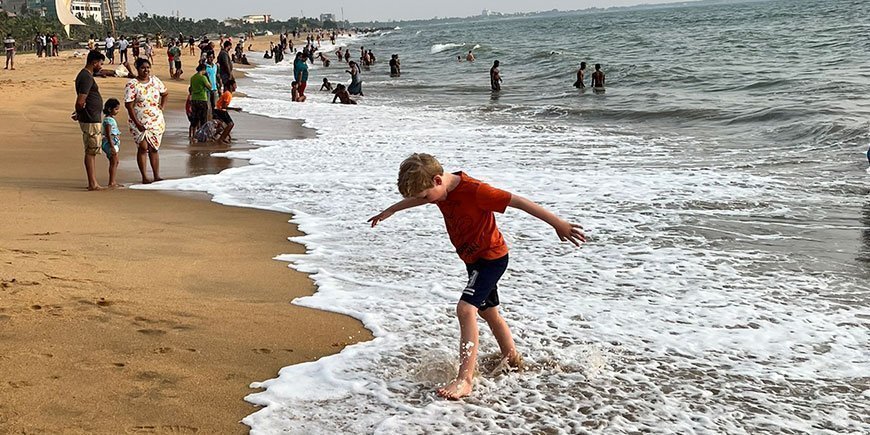 Een jongen loopt aan de waterkant op het gouden strand in Sri Lanka