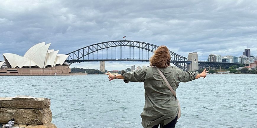 Beate staat voor het Opera House en de Sydney Harbour Bridge in Australië