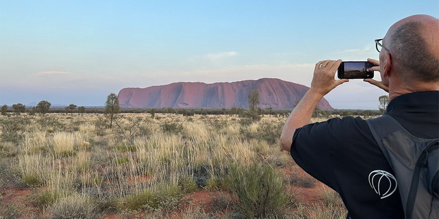 Een man neemt een foto van Uluru in Australië