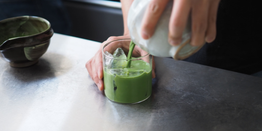 Een persoon giet matcha-thee in een glas