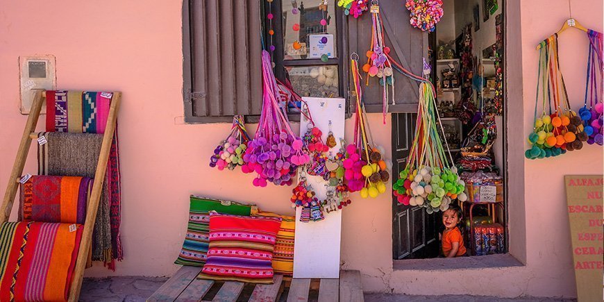 Klein plaatselijk winkeltje in Purmamarca, Argentinië en een meisje dat in de deuropening zit.