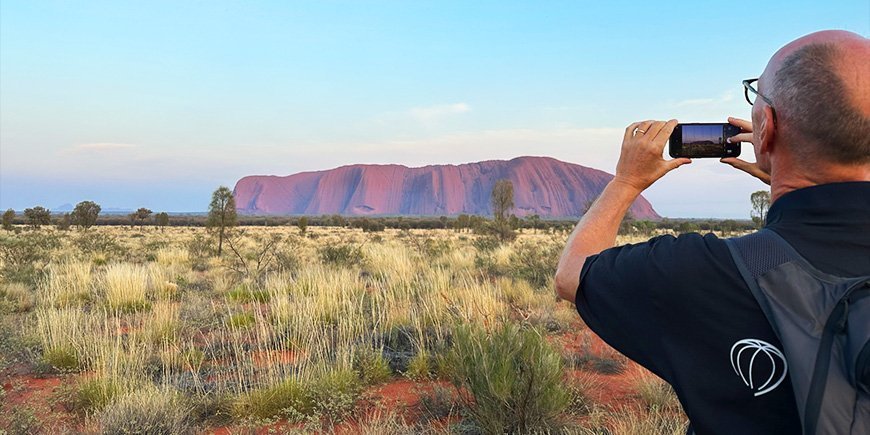 Man maakt foto met mobiele telefoon van Uluru in Australië