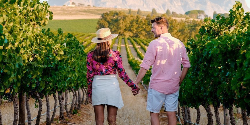 Vrouw en man houden elkaars hand vast in een wijngaard in Zuid-Afrika