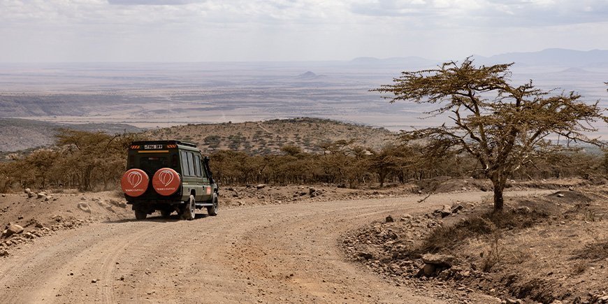 Vierwielaangedreven voertuig met TourCompass-logo gaat op safari in Tanzania