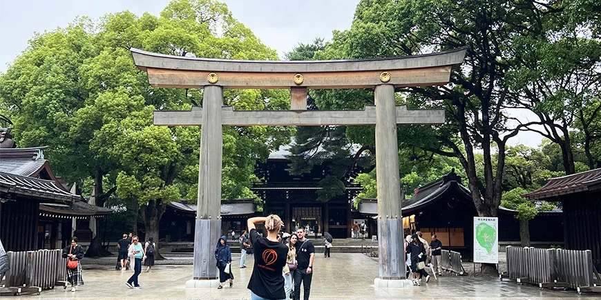 Vrouw die een foto maakt van een stel onder een Torii-poort bij de Meiji-schrijn