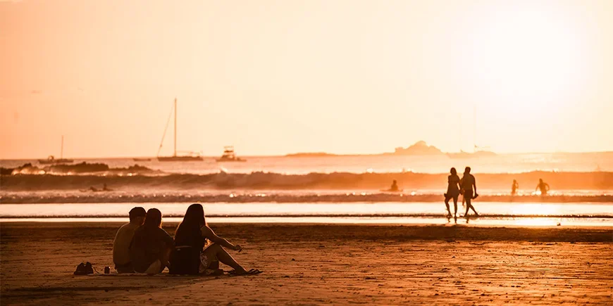 Mensen die genieten van de zonsondergang op het strand van Tamarindo in Costa Rica