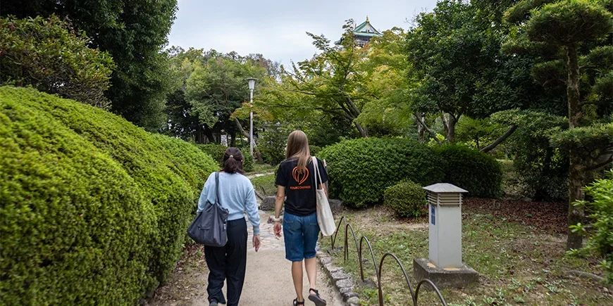 Japanse gids wandelt met een medewerker van TourCompass bij het kasteel van Osaka in Japan