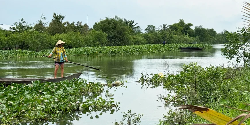 Vrouw die vaart over de Mekongdelta