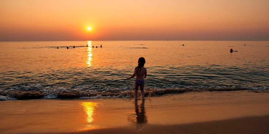 Meisje dat in het water speelt bij Phu Quoc bij zonsondergang