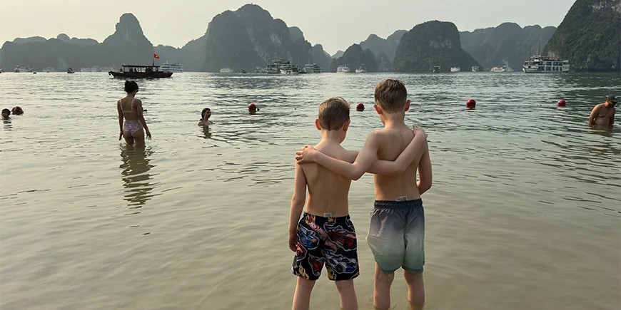 Twee jongens die elkaar omhelzen op een strand in Halong Bay
