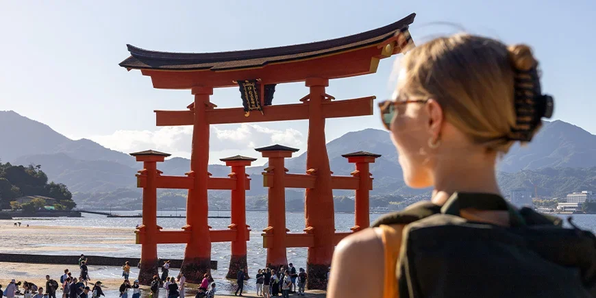 Vrouw kijkt naar het rode heiligdom op het eiland Miyajima in Hiroshima