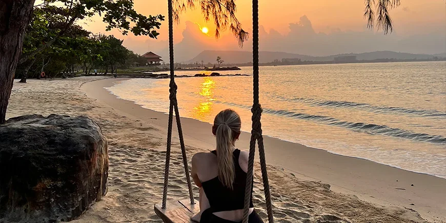 Meisje op een schommel tijdens zonsondergang op het strand van Phu Quoc