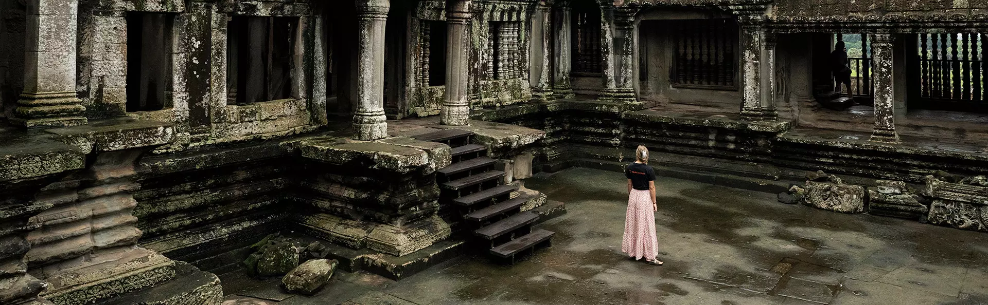 Vrouw in een TourCompass-T-shirt die de ruïnes van Angkor verkent