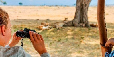 Meisje op safari in Kenia met leeuwen op de achtergrond.
