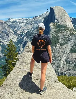 Vrouw in TourCompass t-shirt op klif in Yosemite